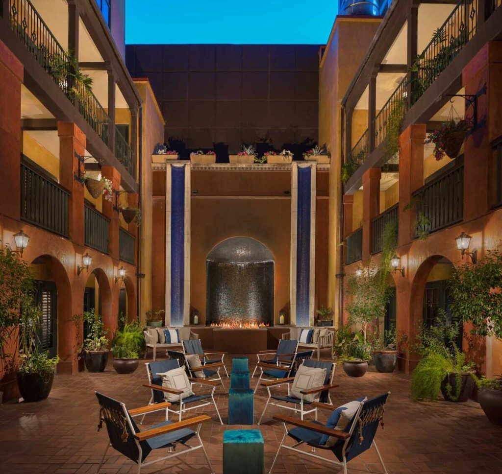 Beautiful Spanish style courtyard with rooms around the perimeter, arched doorways, and a seating area with fire pit