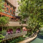 Spanish colonial inspired hotel above the green waters of the Riverwalk in San Antonio Texas
