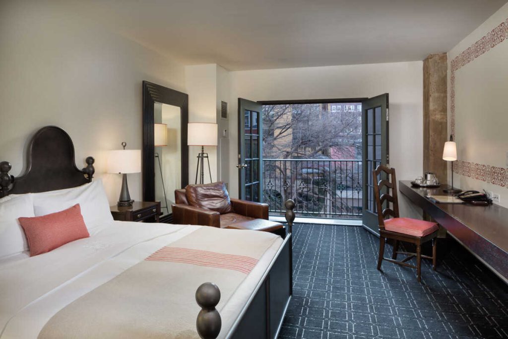 Hotel room with Spanish colonial style furniture and ivory linens with red accents