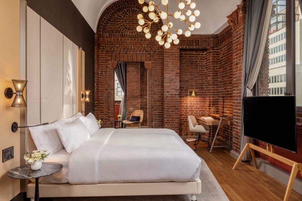 Sunny, spacious hotel suite with exposed brick walls and globe shaped pendant lamp